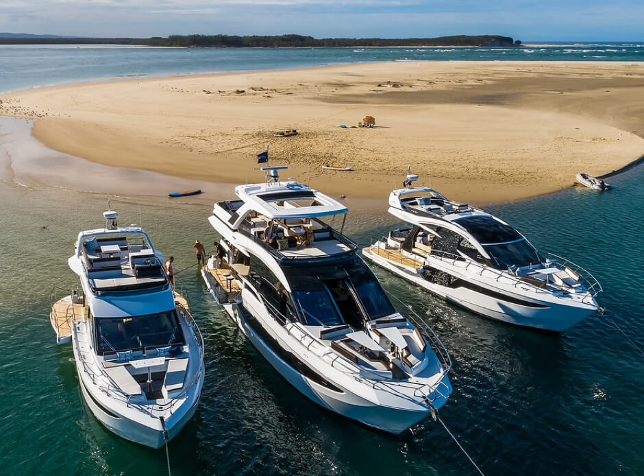 Three Galeon yachts anchored off the shore of a sand bar