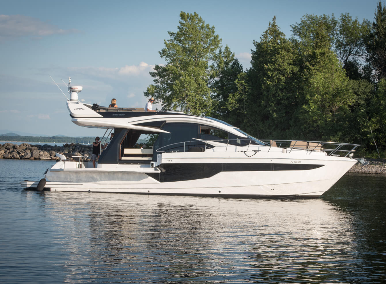 Galeon yacht sitting on the water with people at the stern and on the top deck