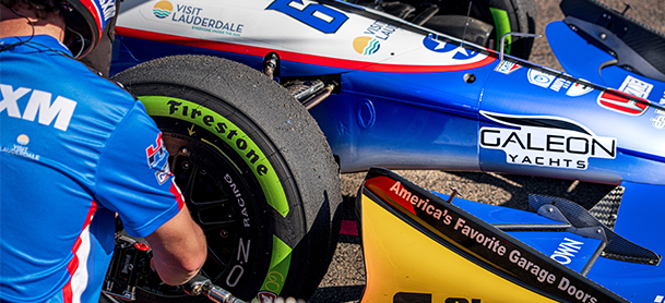 Pit crew checking wheels and lugs on an F1 car with Galeon logo