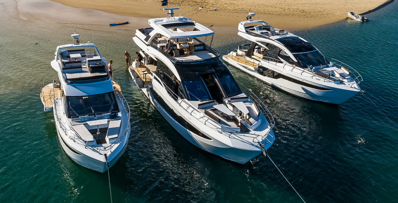 Three Galeon yachts anchored by a sandbar and people in the water behind the yachts
