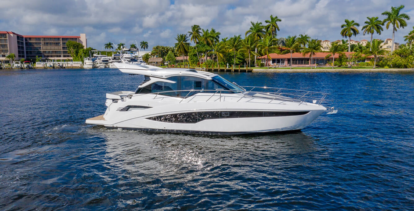 Galeon yacht at a standstill on bright blue water with palm trees on the shoreline
