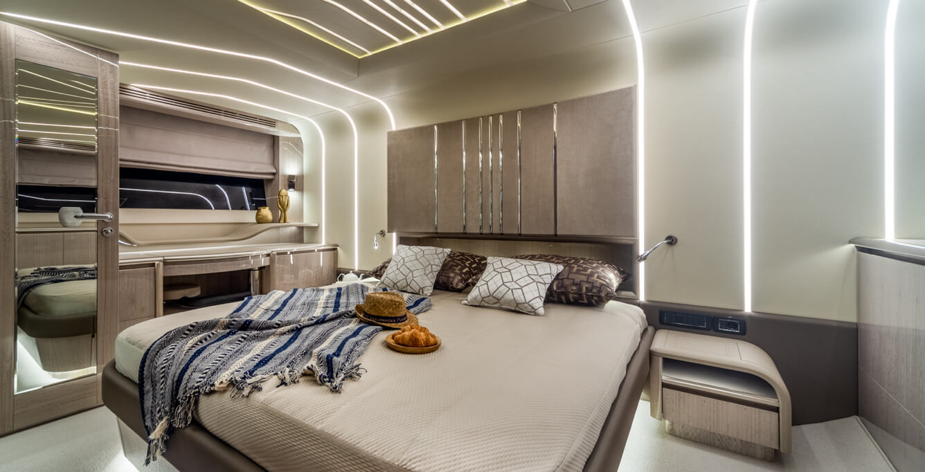 Interior view of a Galeon Yacht cabin with a throw and pillows on the bed