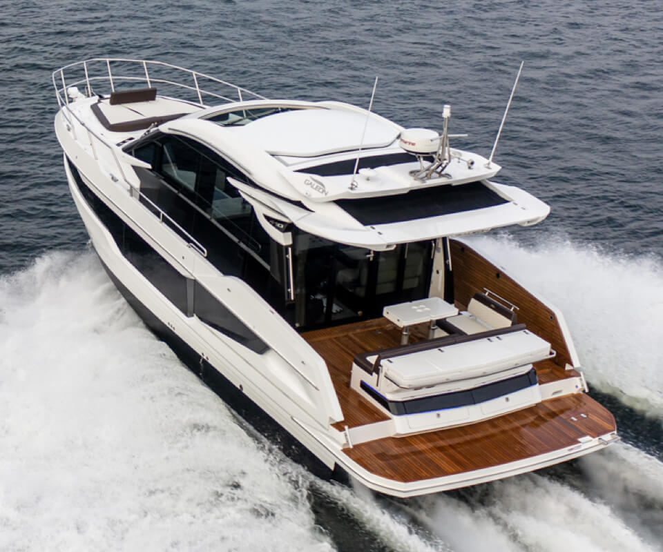 The stern of the Galeon 410 HTC yacht with dark wood deck and white top