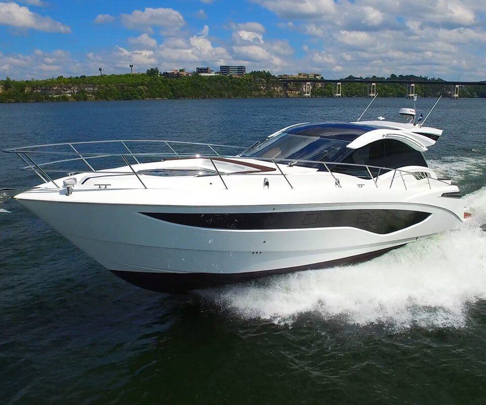 The Galeon 485 HTS yacht speeding on open water with the shoreline behind it