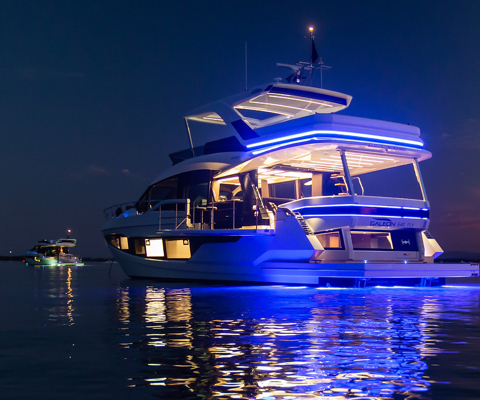 Galeon yacht with interior and rear lights on at night and another boat ahead of it with lights on
