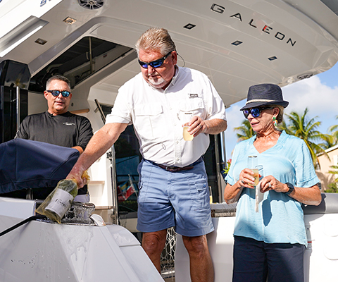New Galeon owners and Galeon team member on Galeron yacht with bottle on champagne