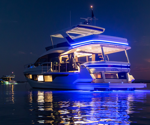 A Galeon yacht with all of its interior and rear LED lights on at night 