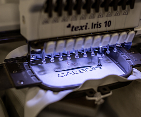 Galeon logo being sewed to the fabric on the sewing machine