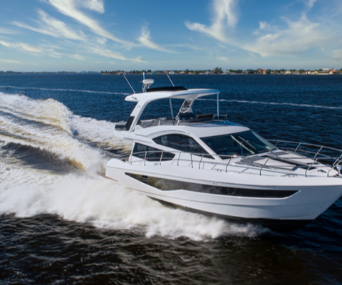 Galeon yacht cruising on the water with a faint shoreline in the distance