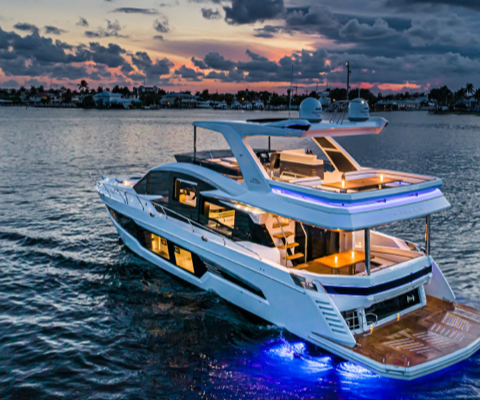 A Galeon yacht with all of its exterior and interior lights on during a cloudy sunset