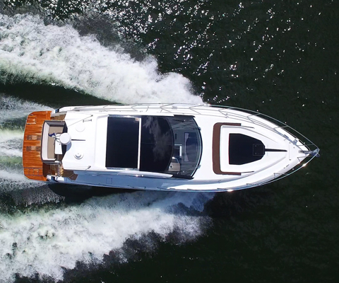Galeon yacht with a wooden deck cruising on the water with a symmetrical wake on either side