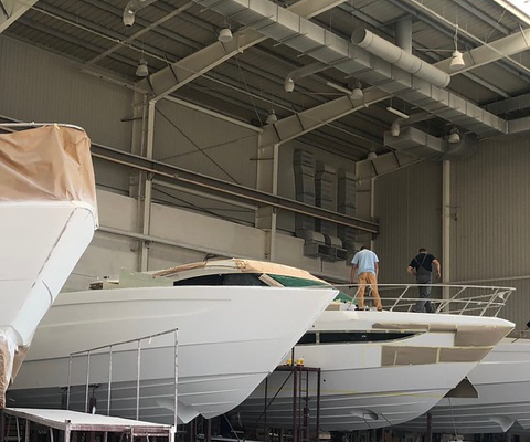 Four Galeon yachts in various stages of production with people working on the exterior shells