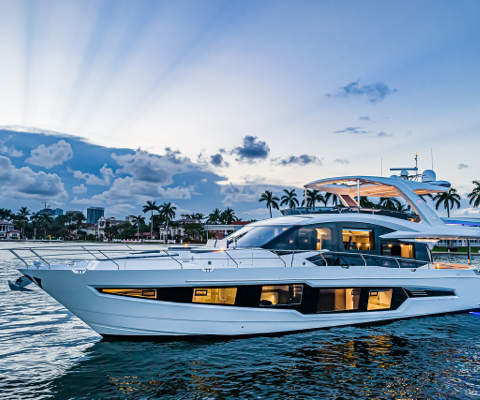 Galeon yacht with lights on in front of palm trees with a cloudy sky and sun rays 